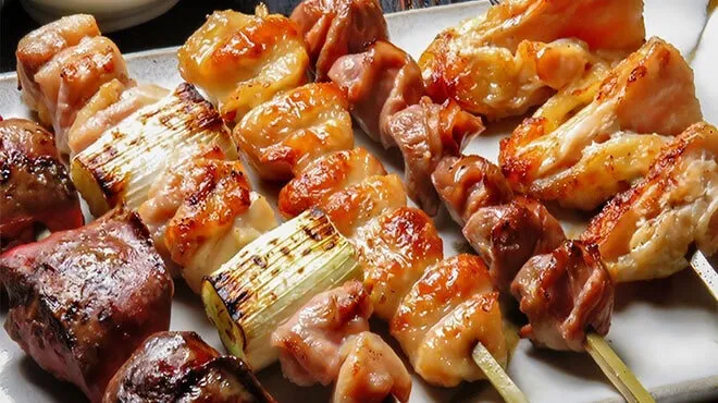 炭火の網の上で焼き色が付いた焼鳥の串